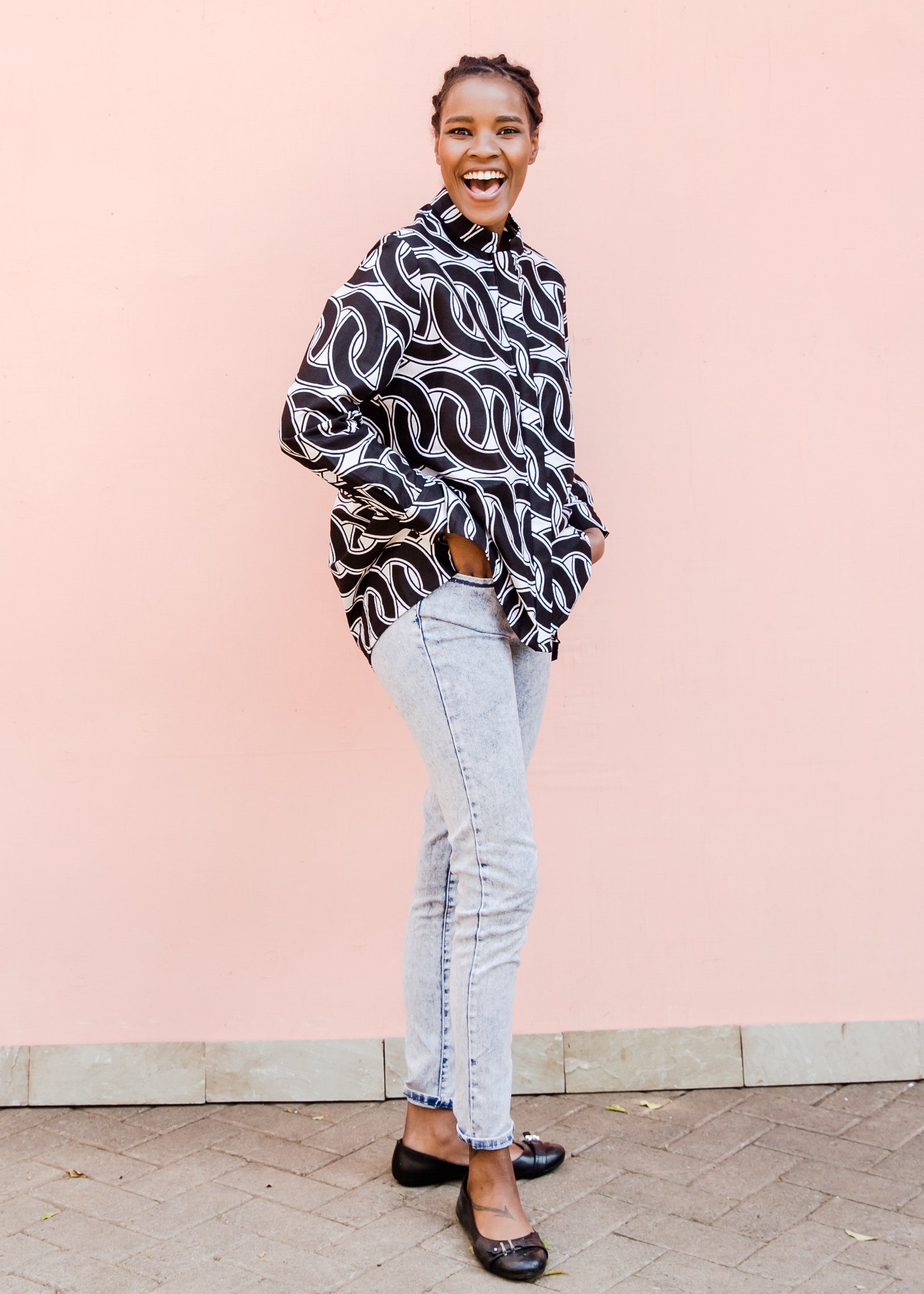Model wearing black and white chain print shirt over jeans.