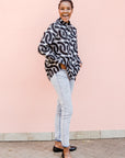 Model wearing black and white chain print shirt over jeans.