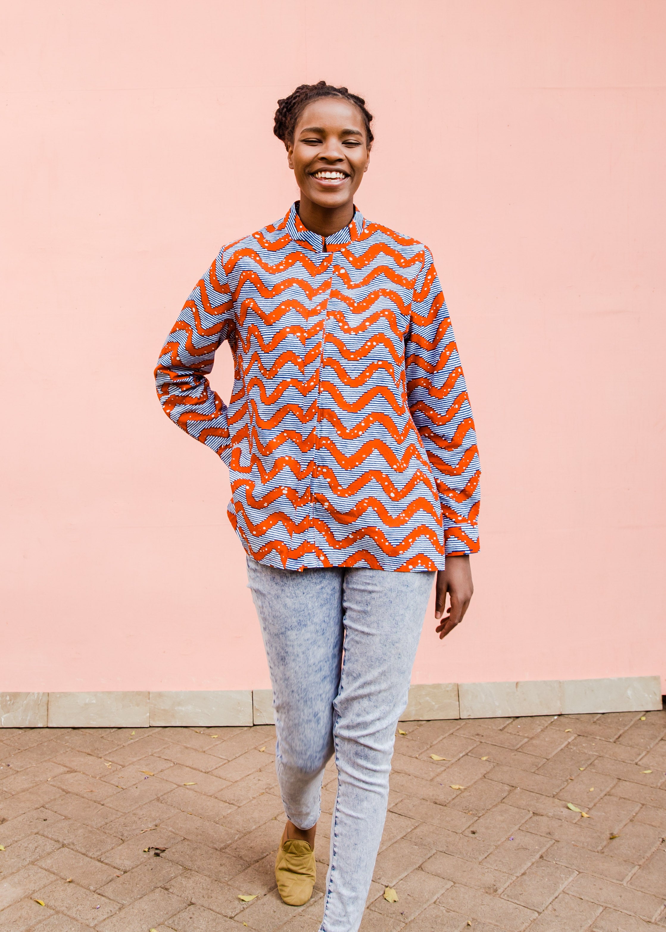 Model wearing blue and red zig zag print long sleeved blouse, paired with jeans and tan flats.
